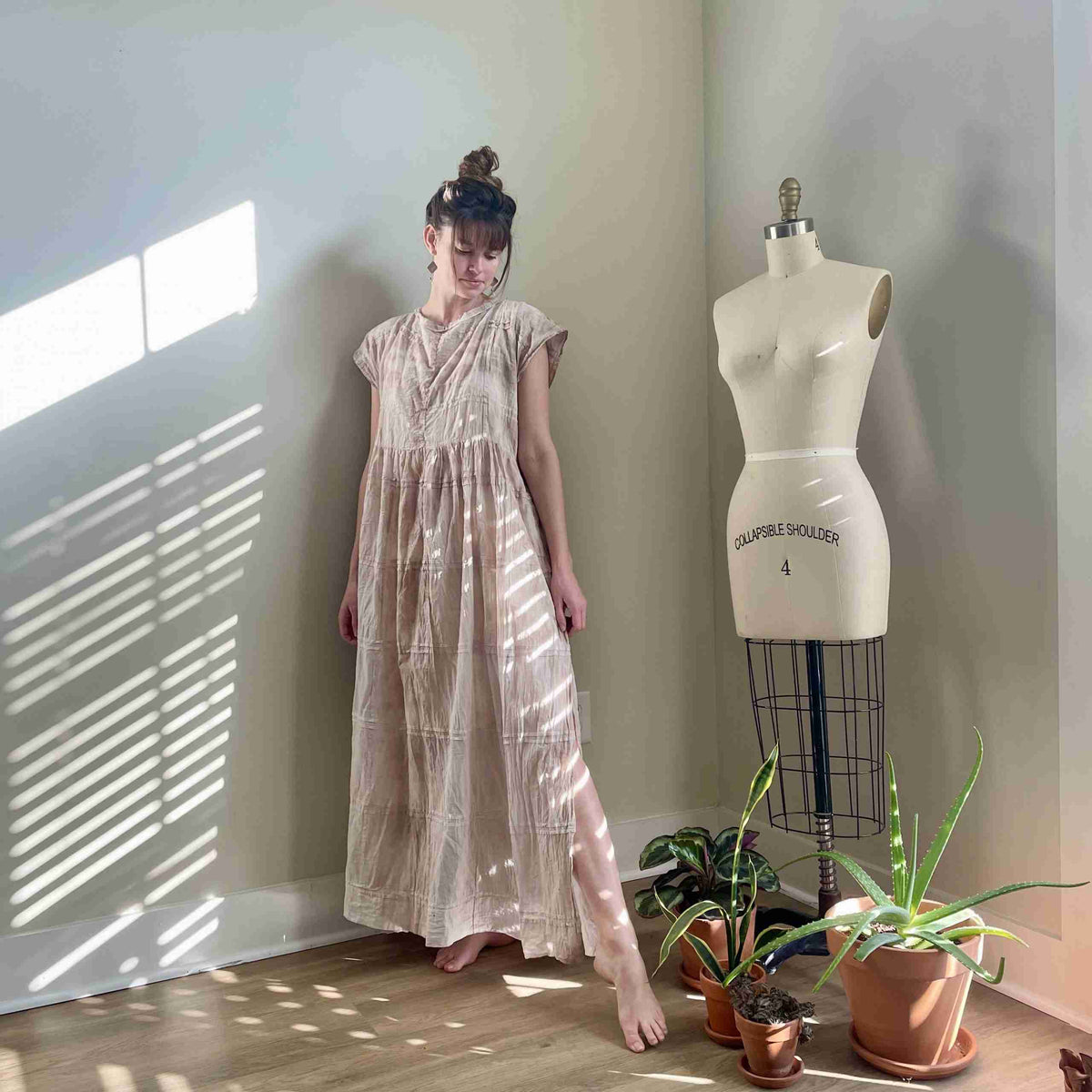 a woman standing next to a dress on a mannequin.