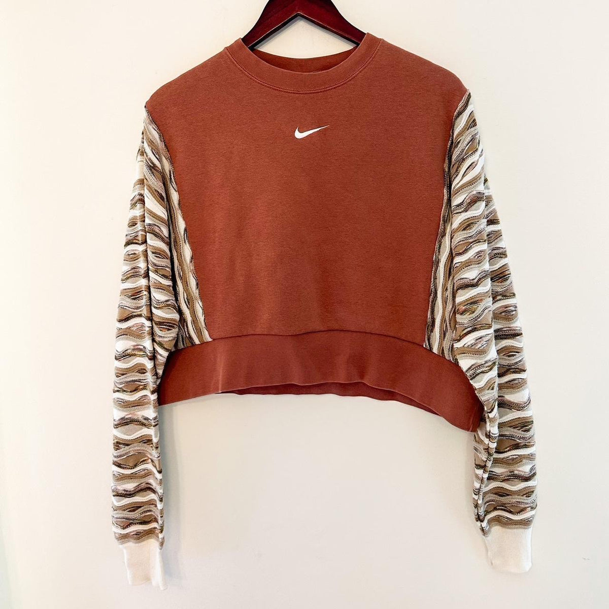 A nike cropped sweatshirt hanging on a hanger.