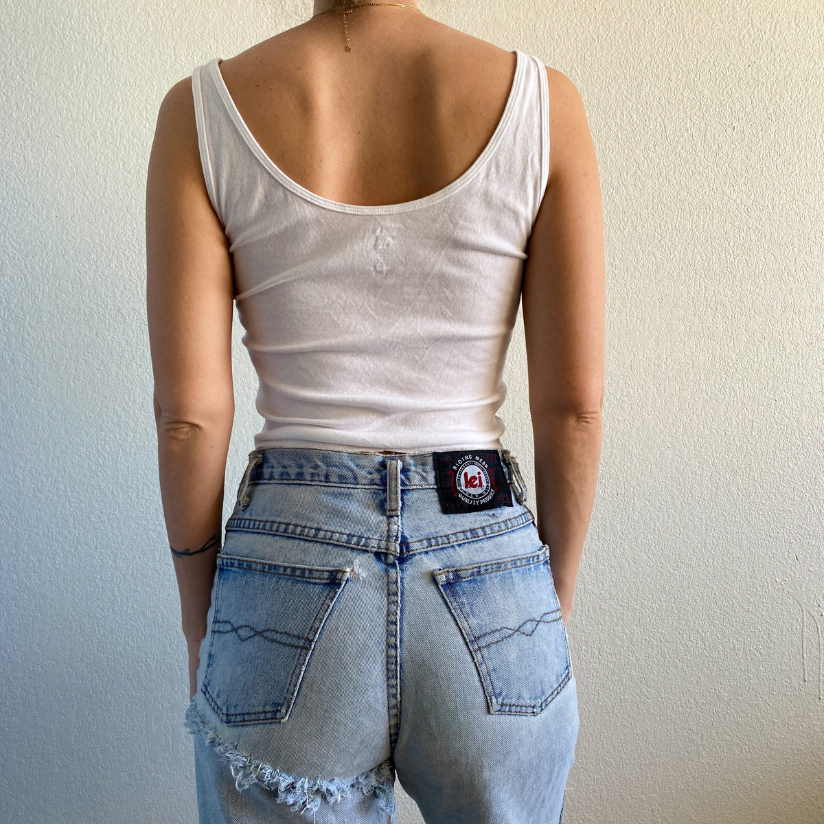 A woman wearing a 1of1 wolves tank top and jeans.