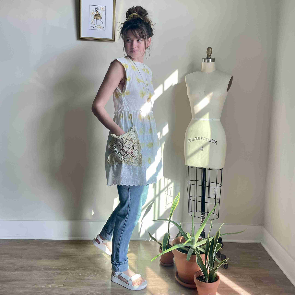 a woman standing next to a dress form.