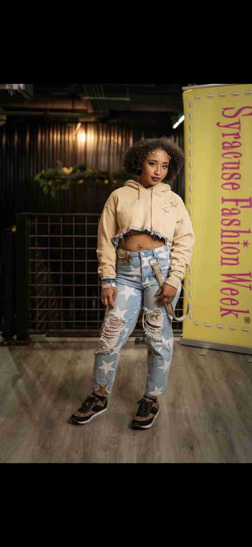 a woman standing on a wooden floor wearing ripped jeans.