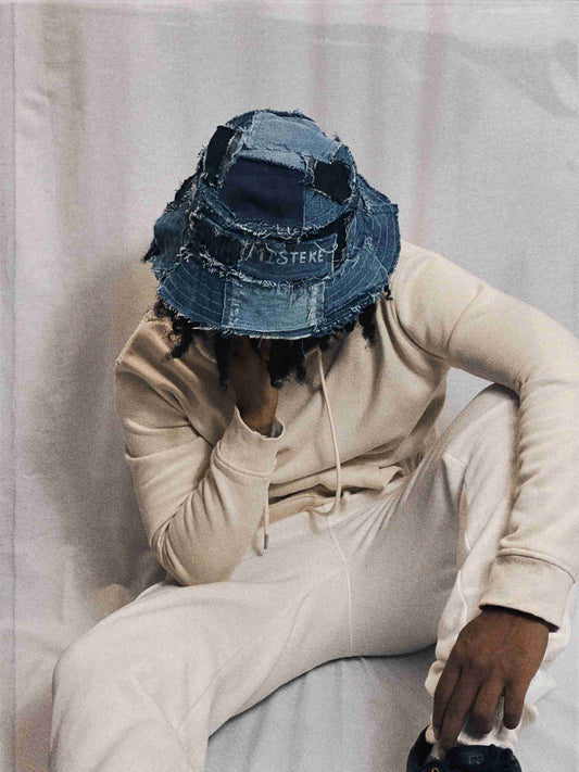 a man sitting on a bed wearing a hat.