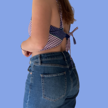 A woman wearing a gingham top and jeans.