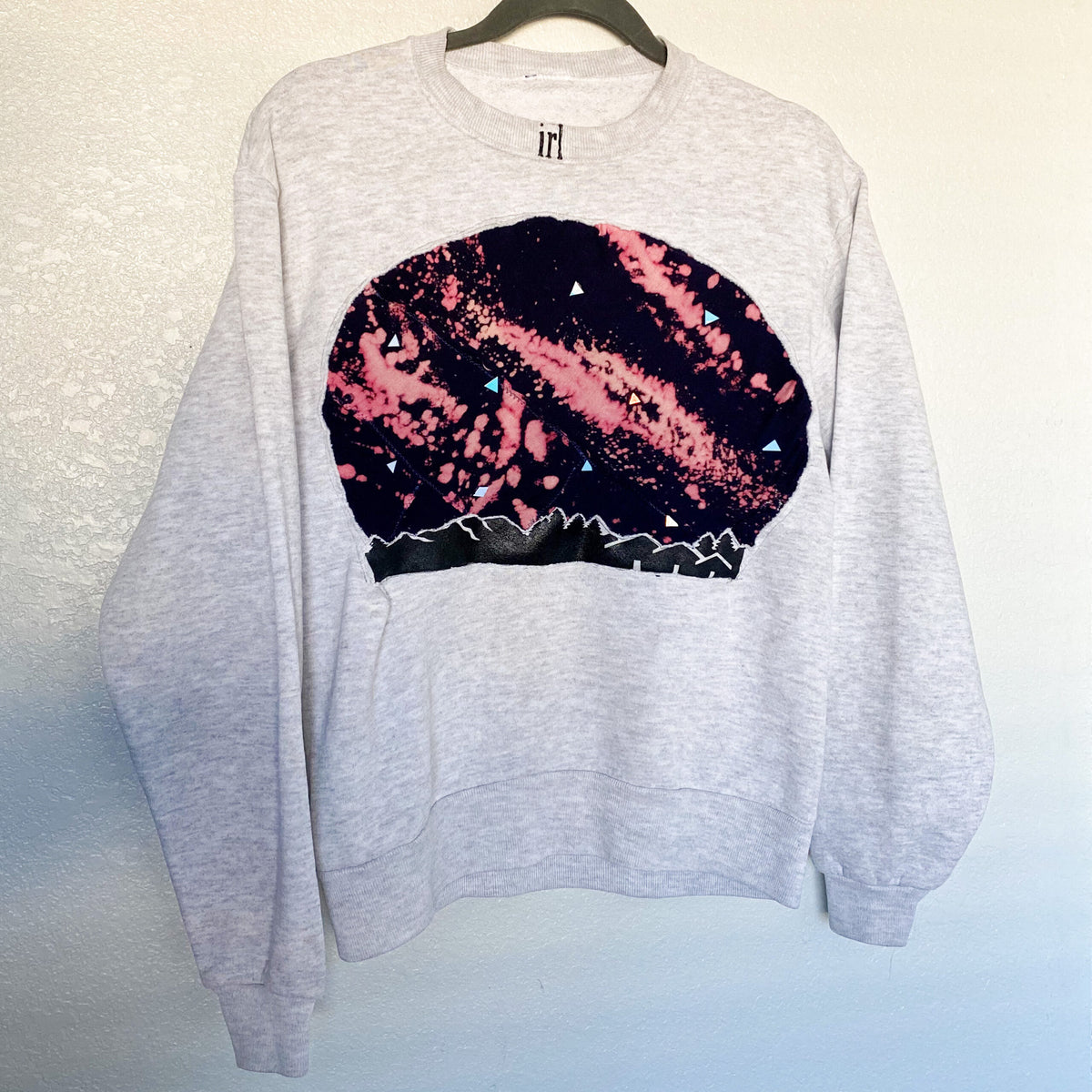 A grey sweater with a graphic design on it.