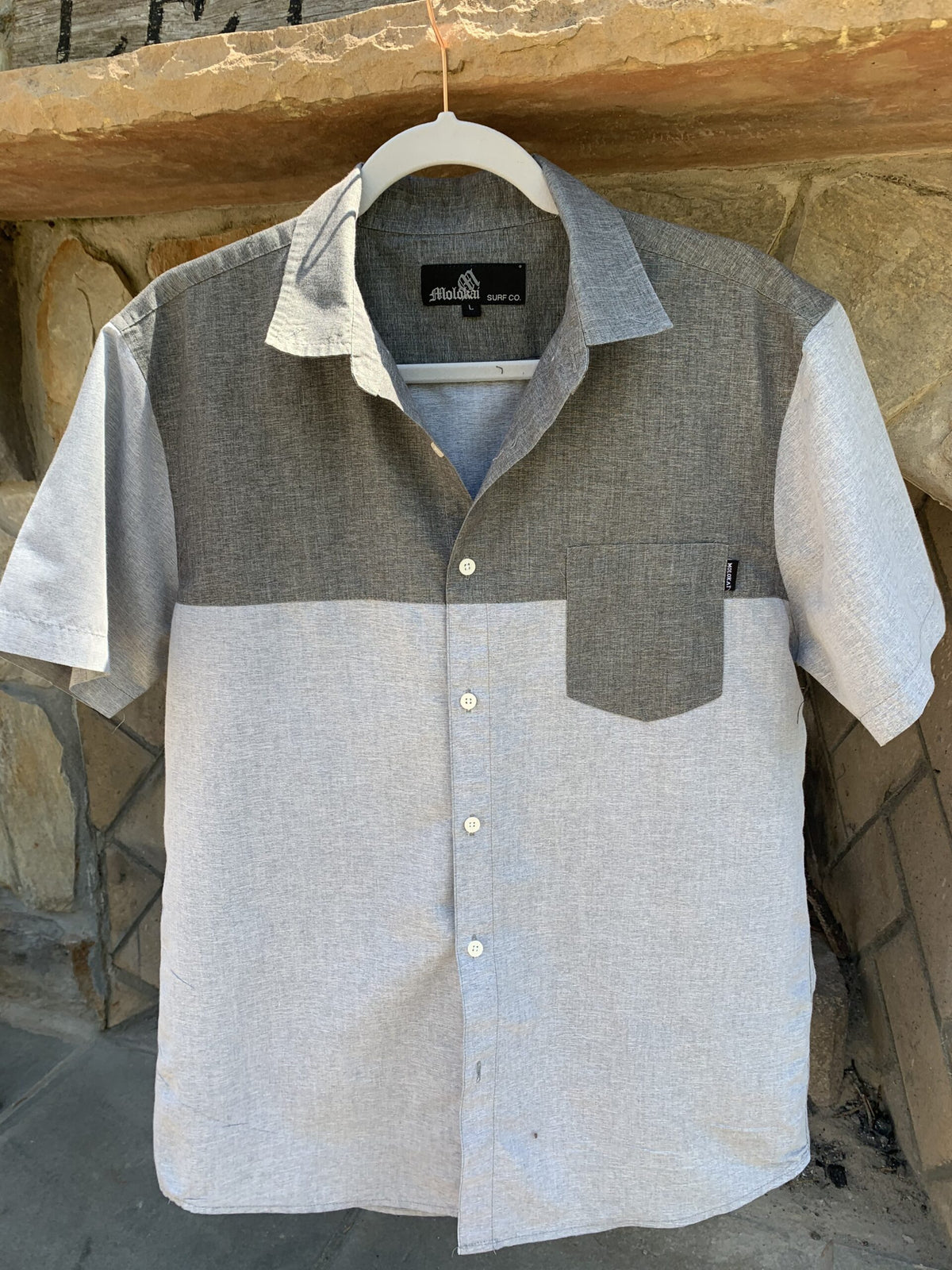 a gray and white shirt hanging on a stone wall.