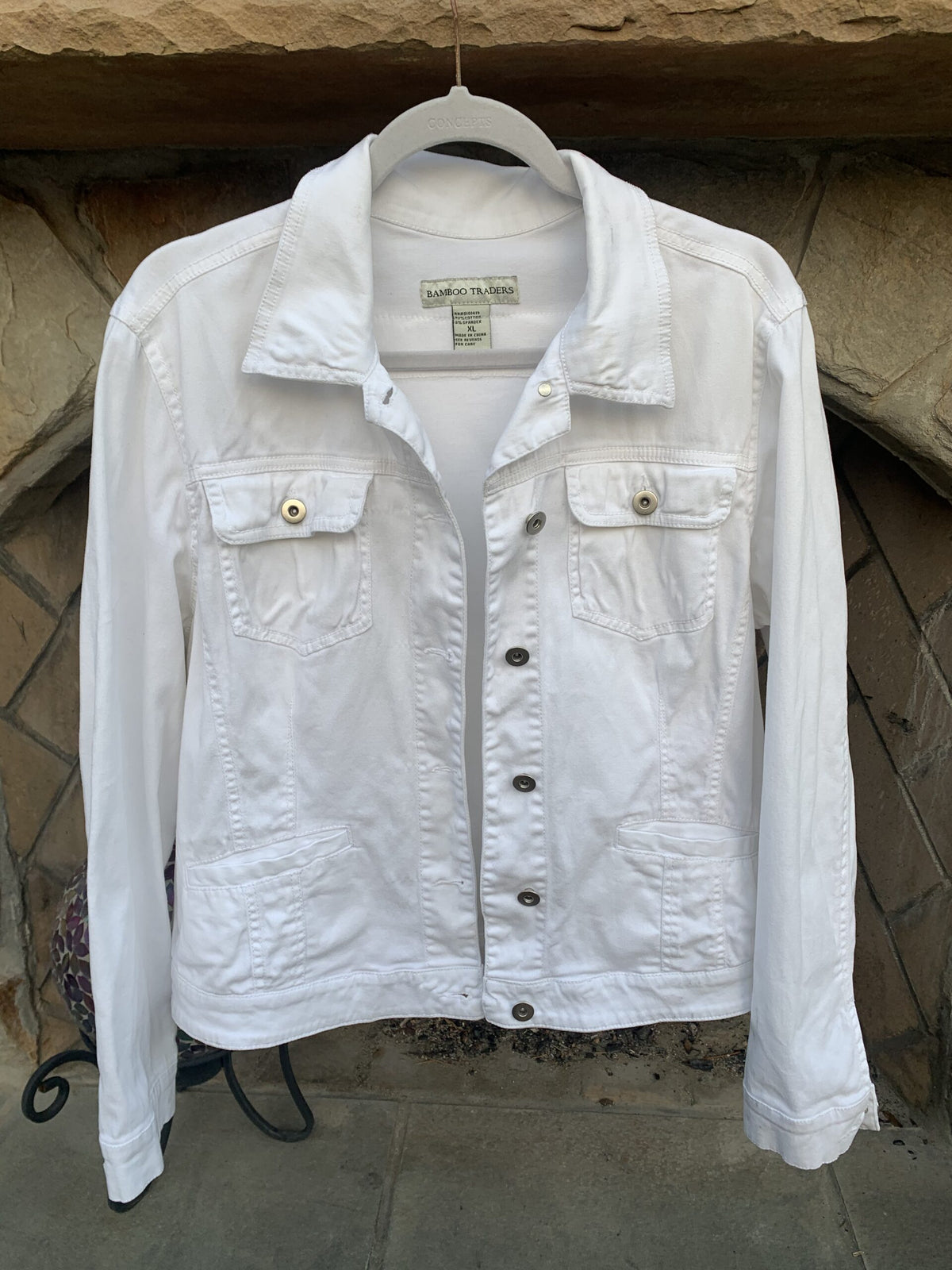 Mick Jagger Swagger White Denim Jacket hanging on a stone wall.