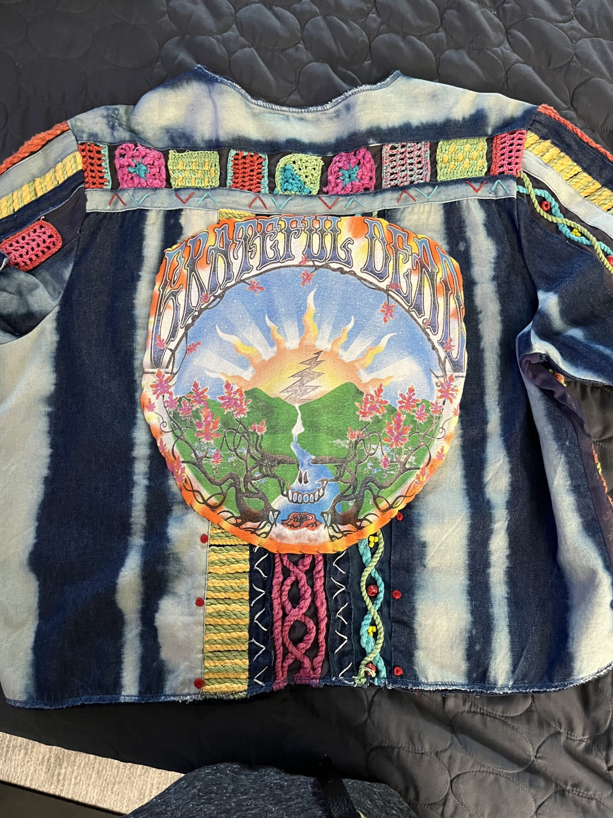 A woman is wearing a jacket with a tie dye design on it.