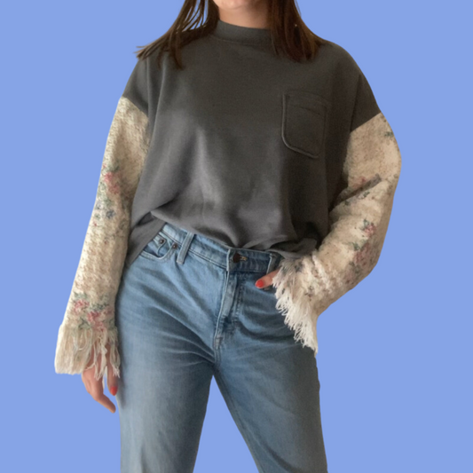 A woman wearing jeans and a sweater with floral sleeve.