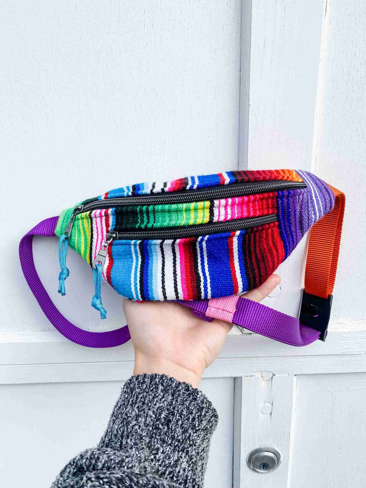a person is holding a multicolored purse in front of a door.