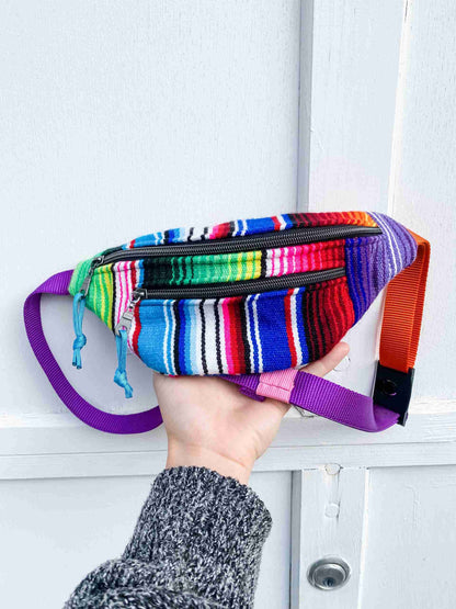 a person is holding a multicolored purse in front of a door.