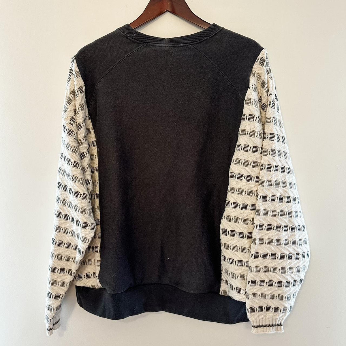 A Reworked Vintage Champion Neutral Crewneck sweater hanging on a wall.