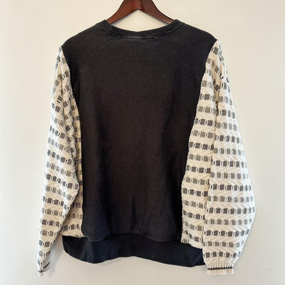 A Reworked Vintage Champion Neutral Crewneck sweater hanging on a wall.