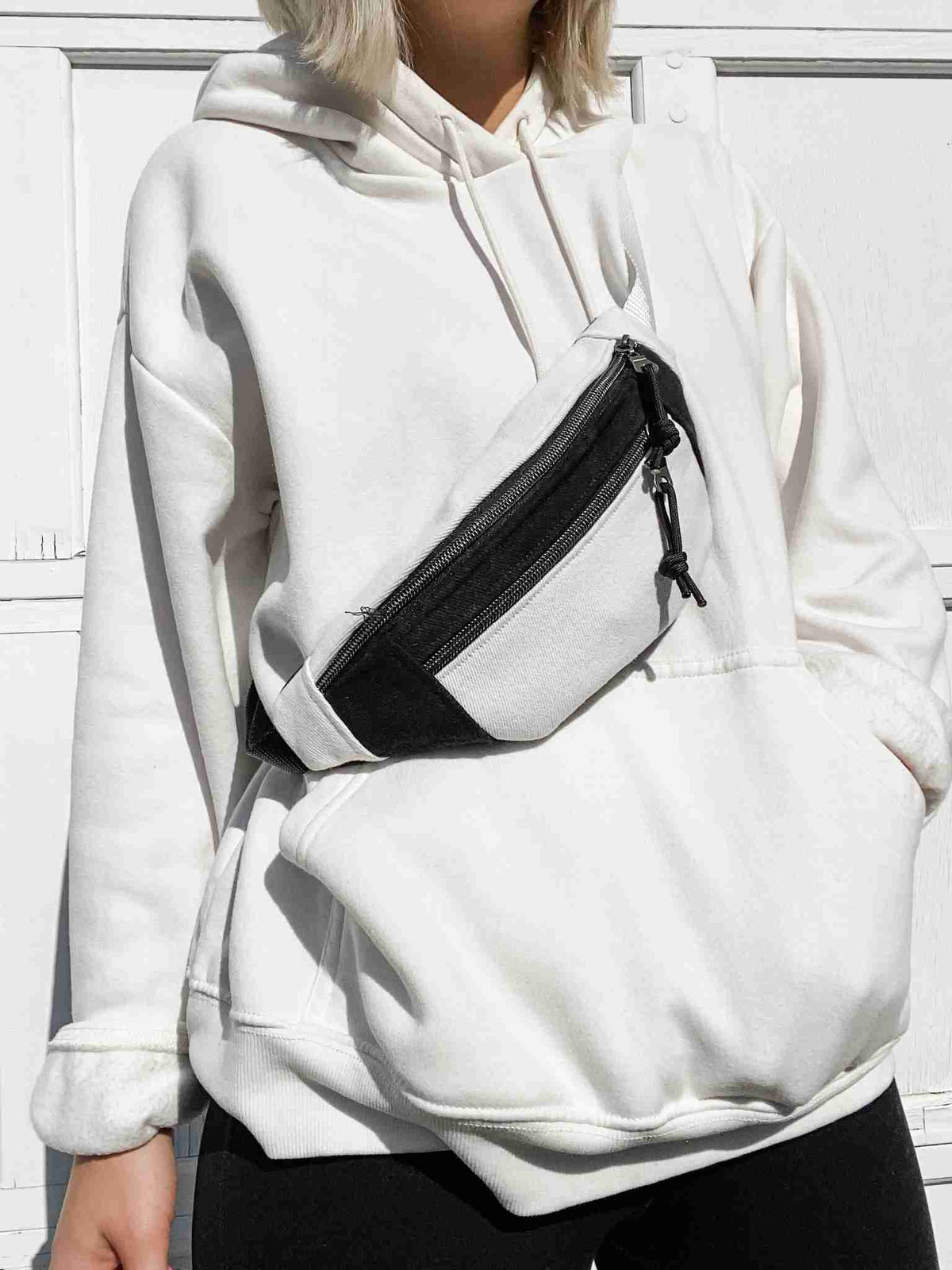 a woman wearing a white sweatshirt and black pants.