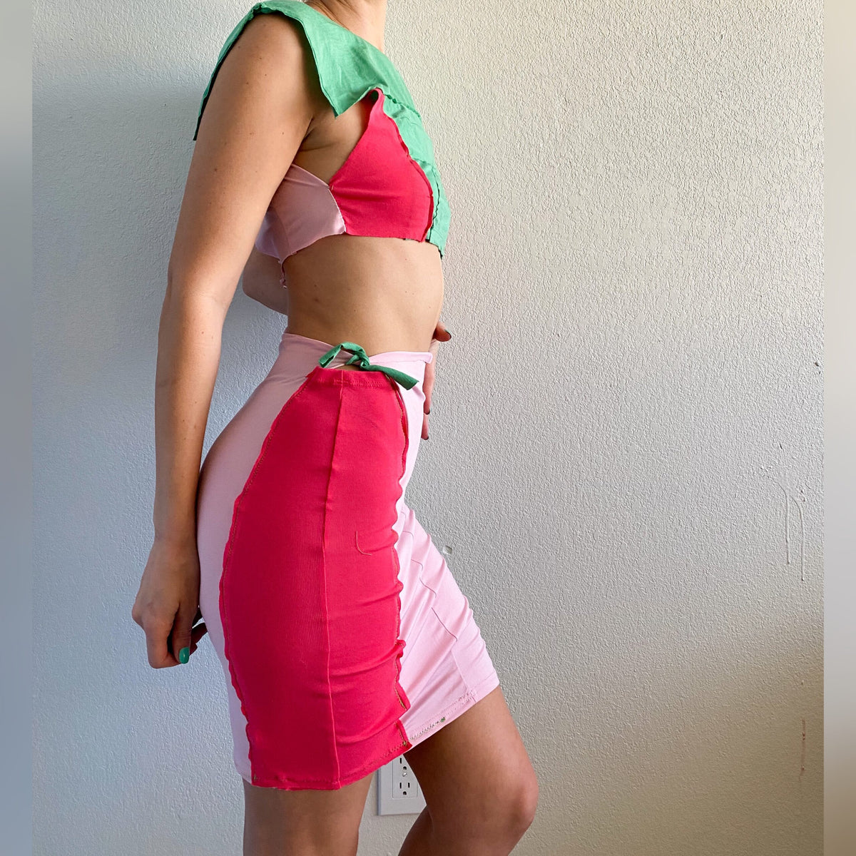 A woman in a 1of1 mint pink berry crop top and skirt set.