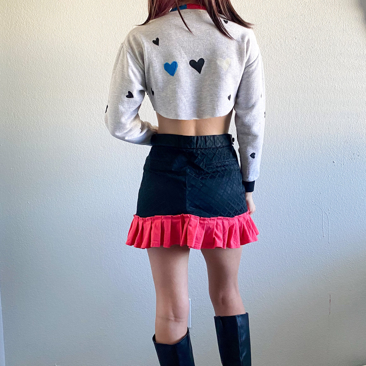 A woman wearing a skirt and boots.