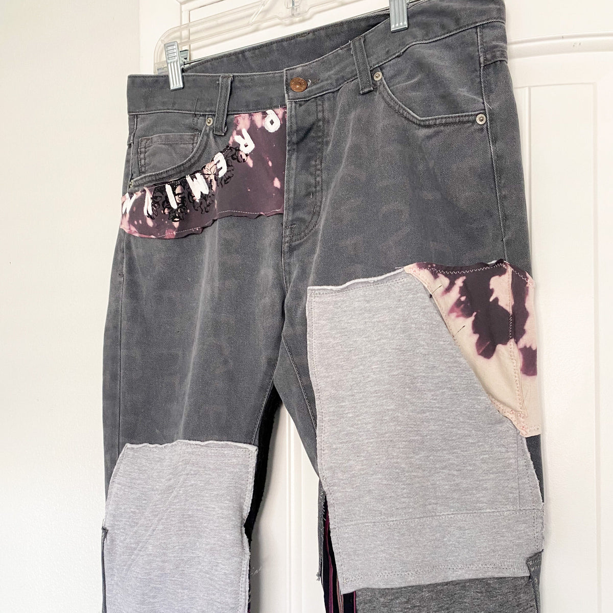 A pair of patched jeans hanging on a door.