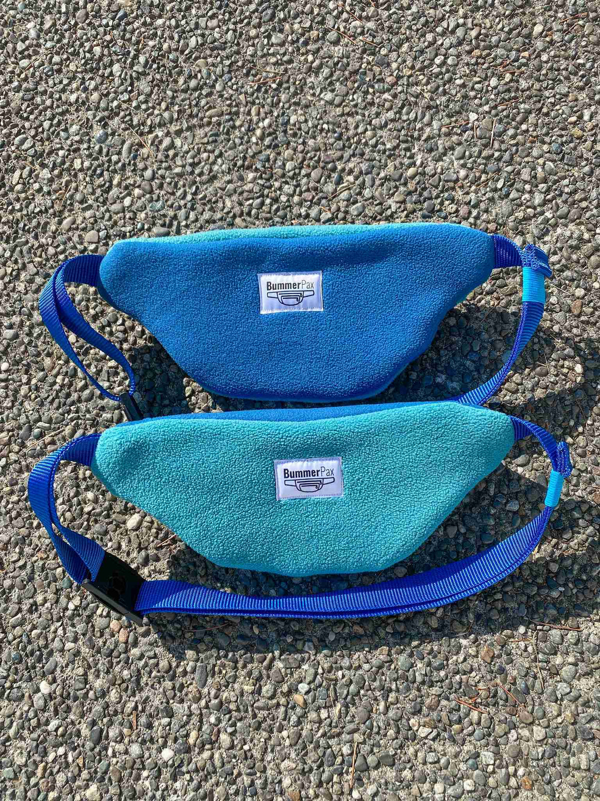 a pair of blue bags sitting on top of a gravel road.
