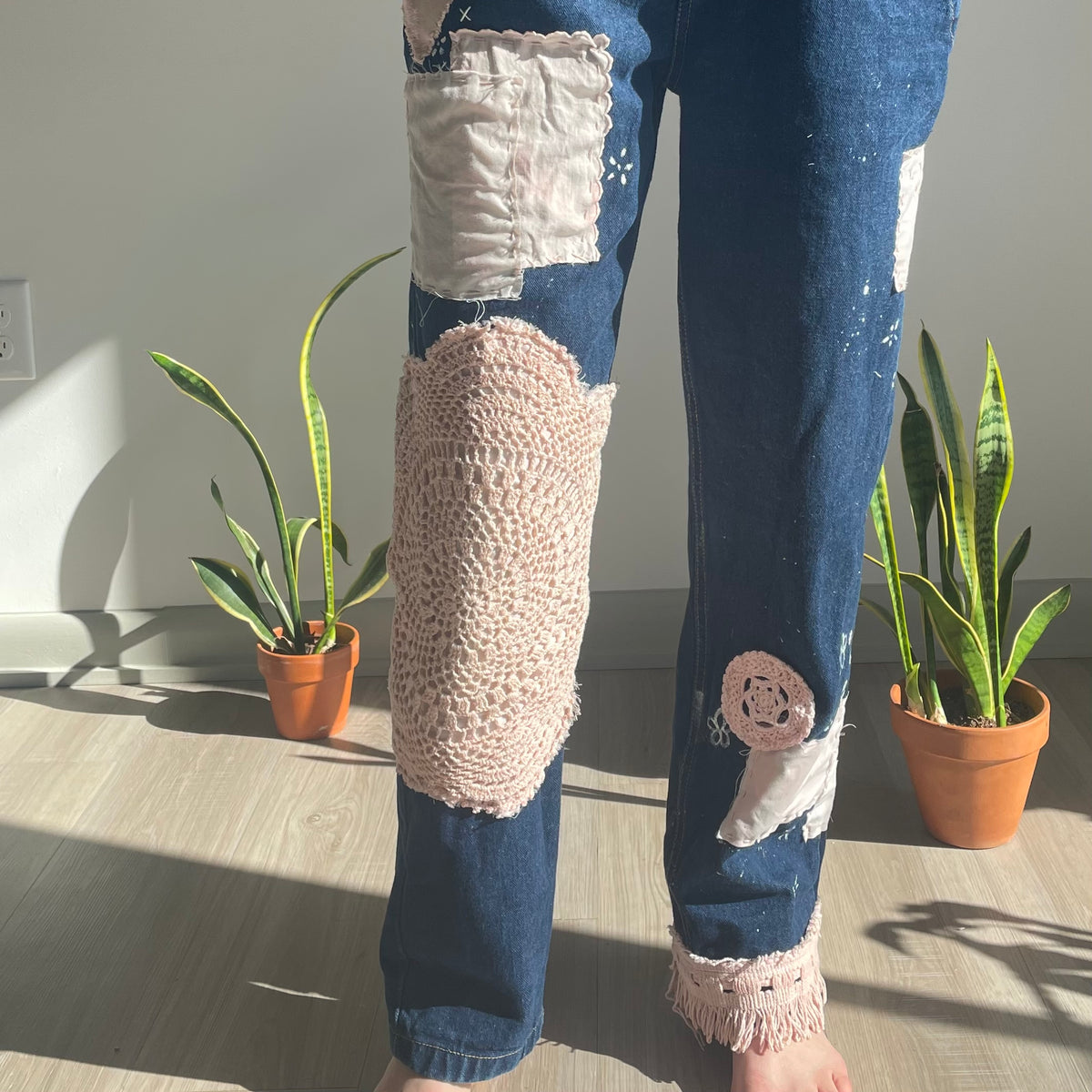 A person wearing a pair of jeans with patches on them.