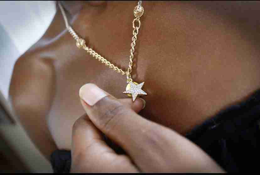 a close up of a person holding a star necklace.
