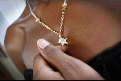a close up of a person holding a star necklace.