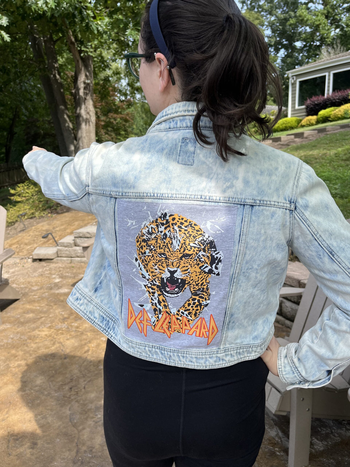 A woman wearing a denim jacket with a tiger on it.