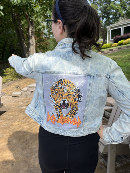A woman wearing a denim jacket with a tiger on it.