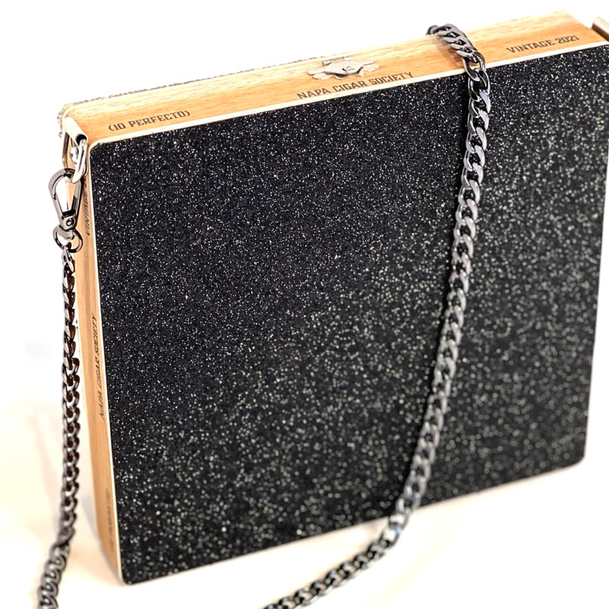 A stylish black glittering shoulder bag with a metallic chain strap, made from an upcycled wooden cigar box.