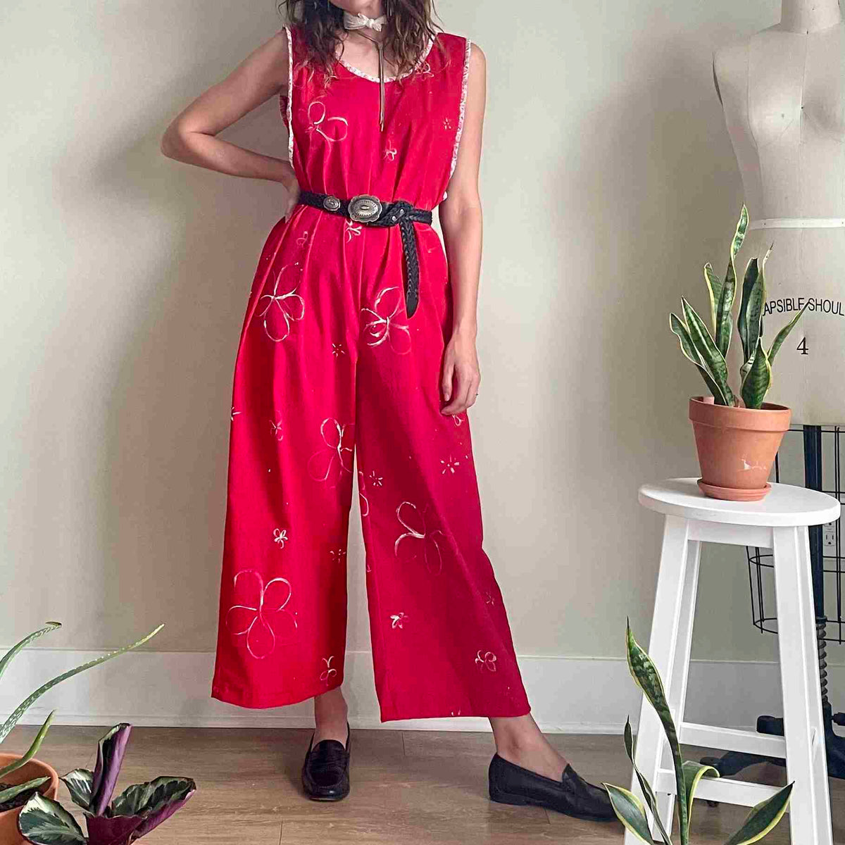 a woman standing in front of a wall wearing a red jumpsuit.