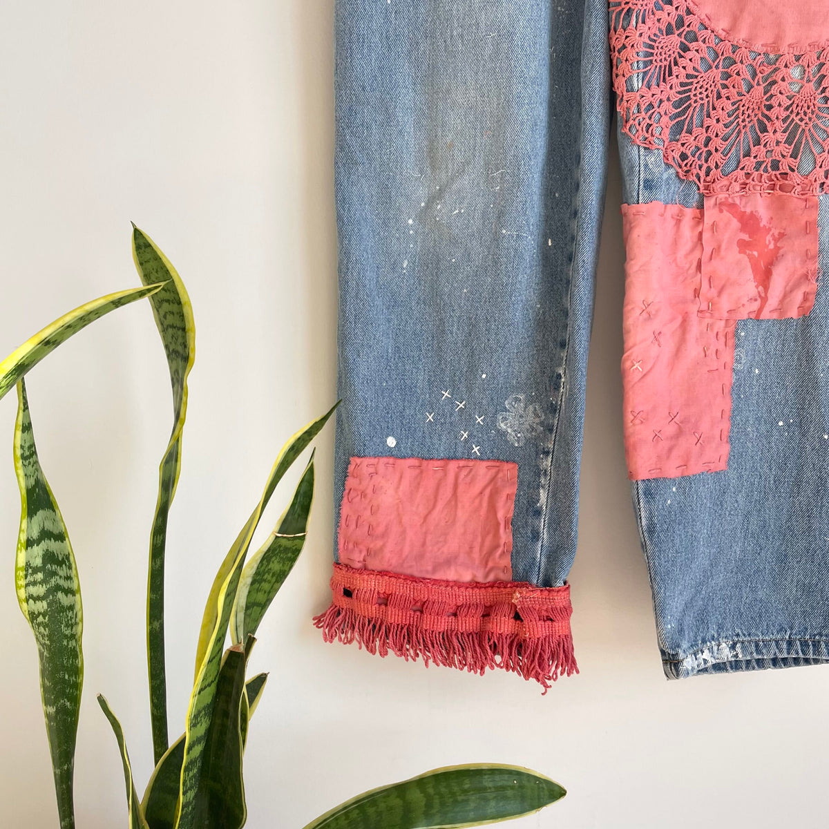 A pair of patched jeans hanging on a wall.