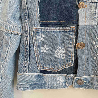 a jean jacket with a flower design on it.