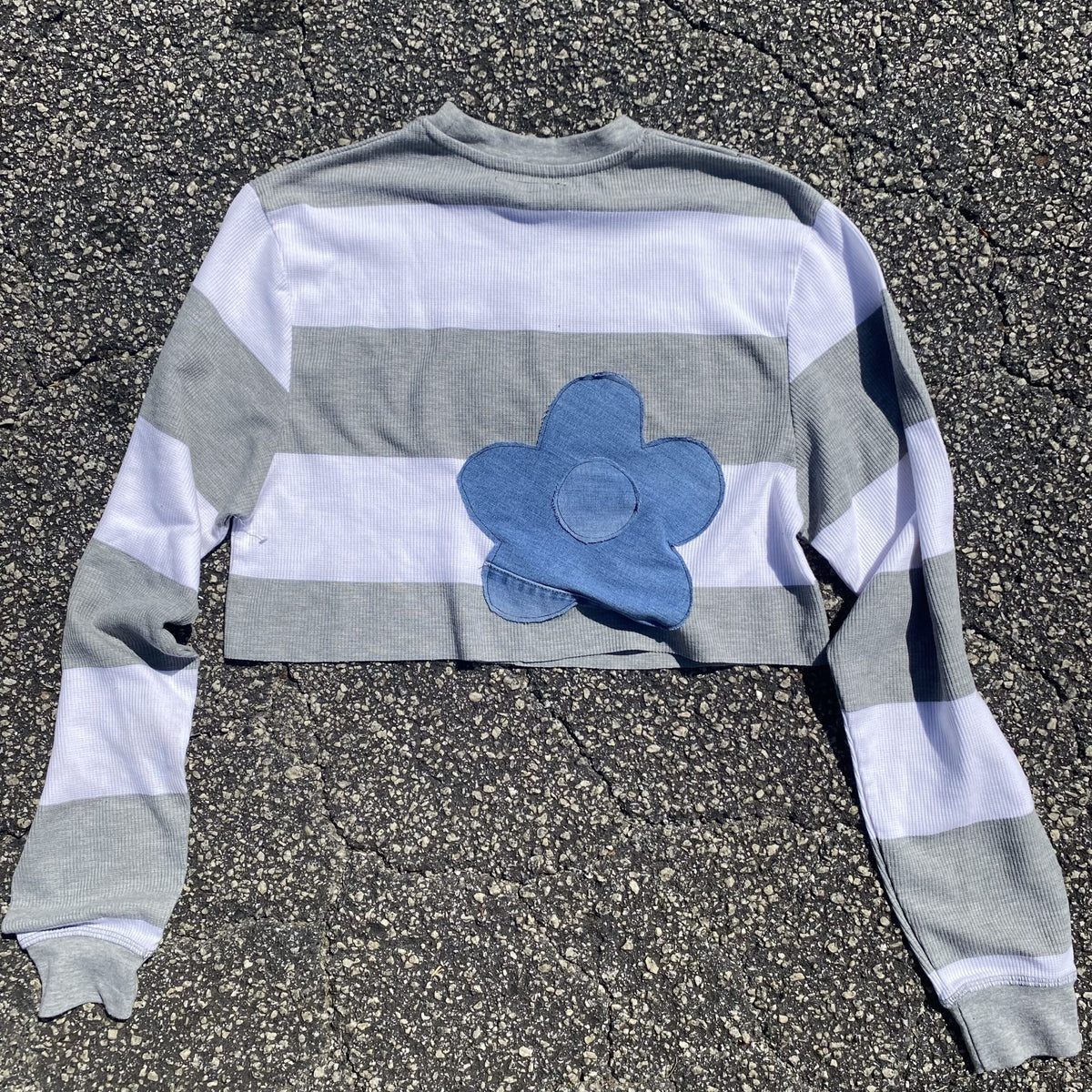 a striped shirt with a blue flower on it.
