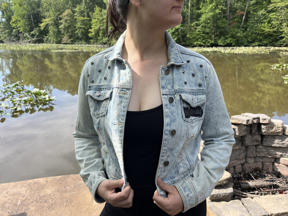 A woman wearing a denim jacket standing next to a body of water.