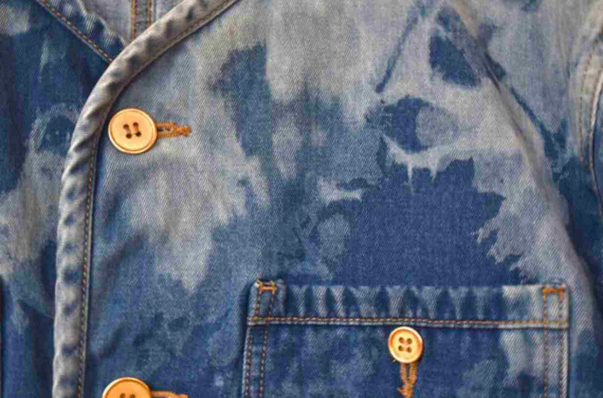 a tie dye denim jacket with buttons on the back.