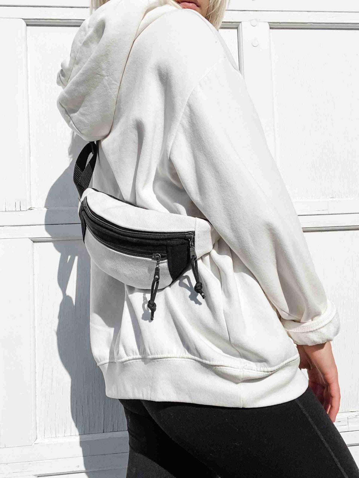 a woman wearing a white hoodie and black pants.