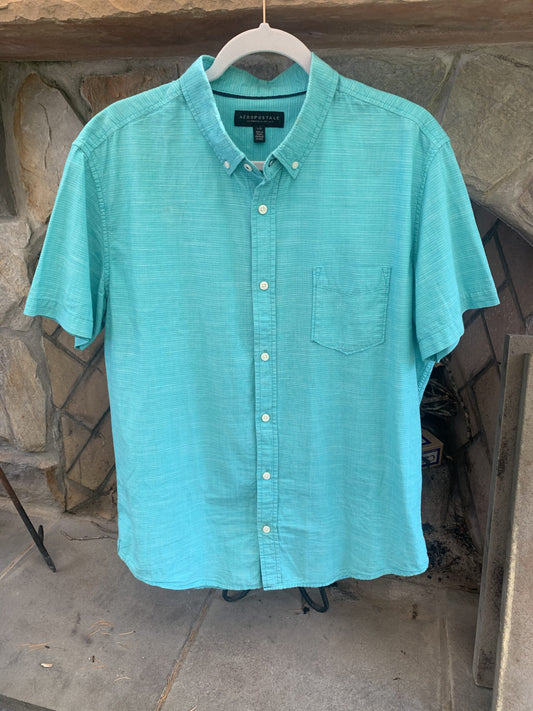 A Rolling Stones logo aqua button up shirt hanging on a clothes rack.