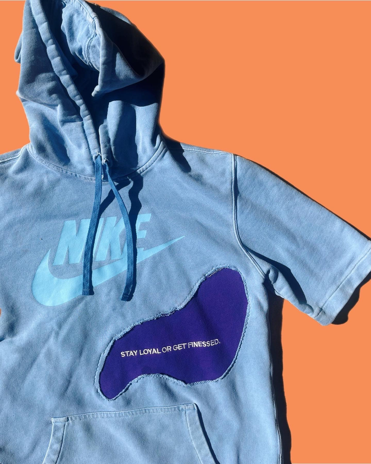 a blue hoodie with a purple shoe on it.