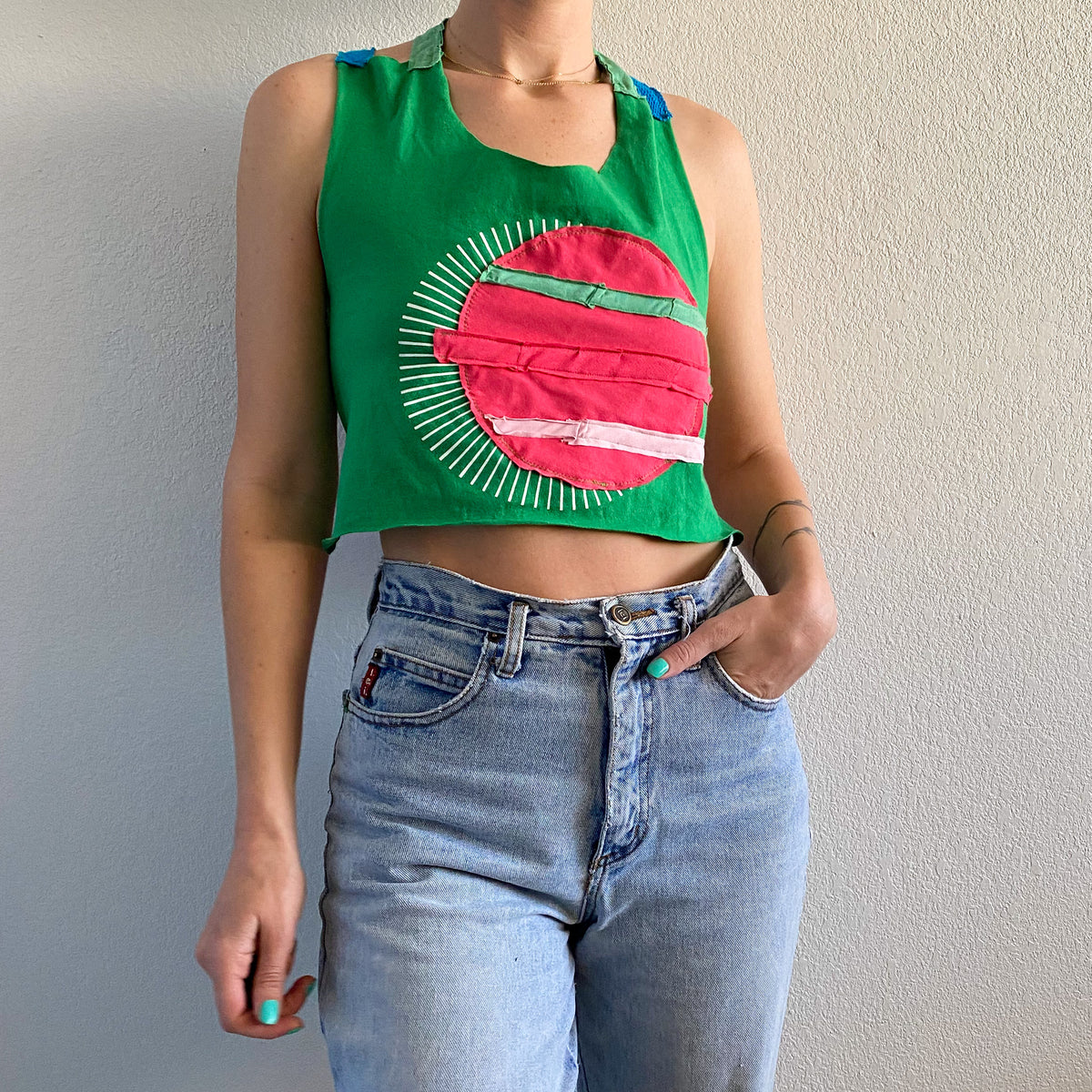 A woman wearing a 1of1 watermelon cross back halter top and jeans.