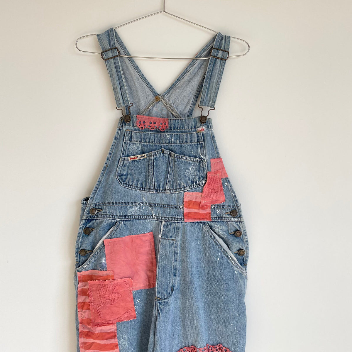 A pair of denim overalls hanging on a wall.