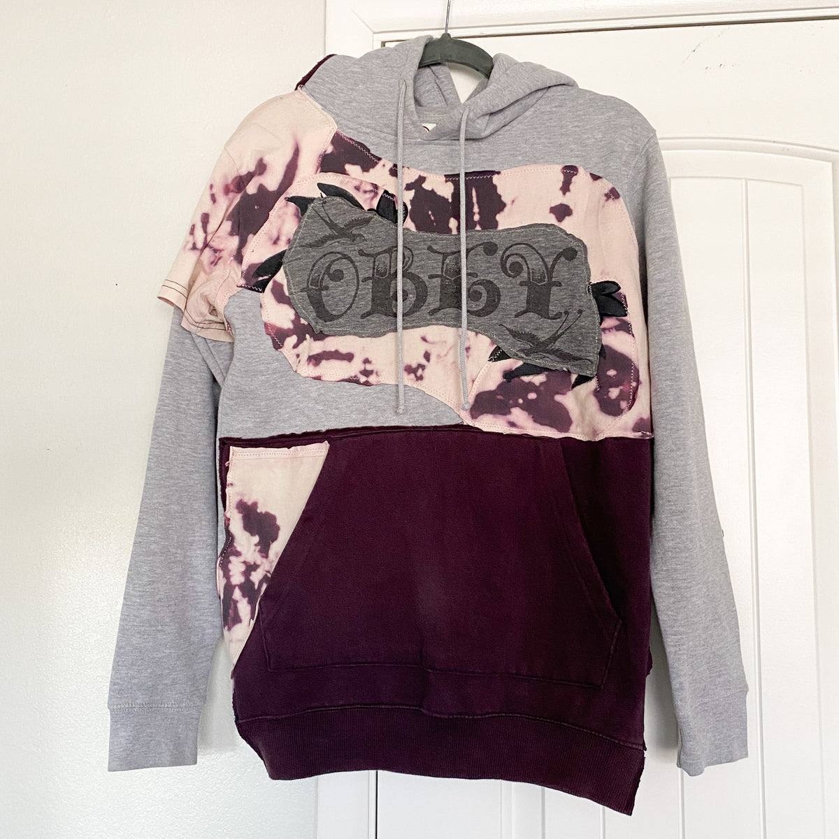 A tie dye hoodie hanging on a door.