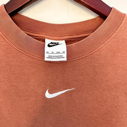 An orange nike t - shirt hanging on a hanger.