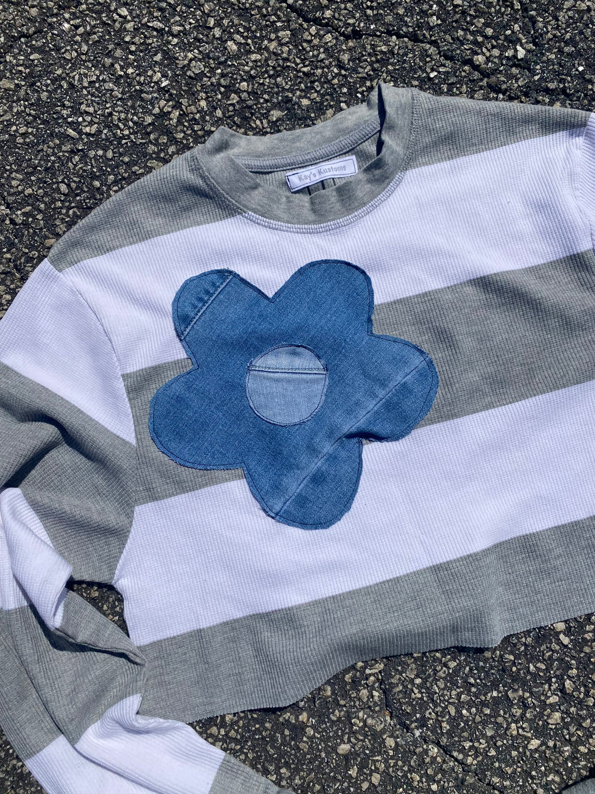 a striped shirt with a blue flower on it.