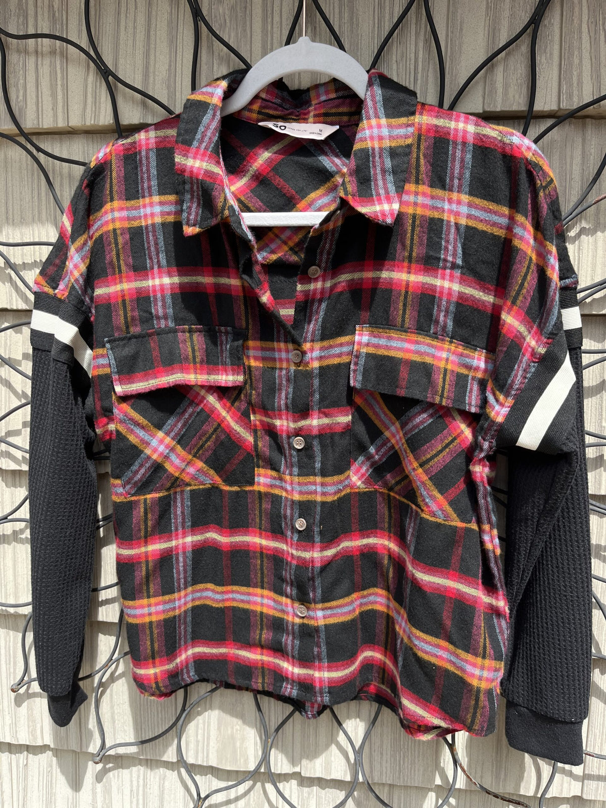A black and red plaid shirt hanging on a wall.