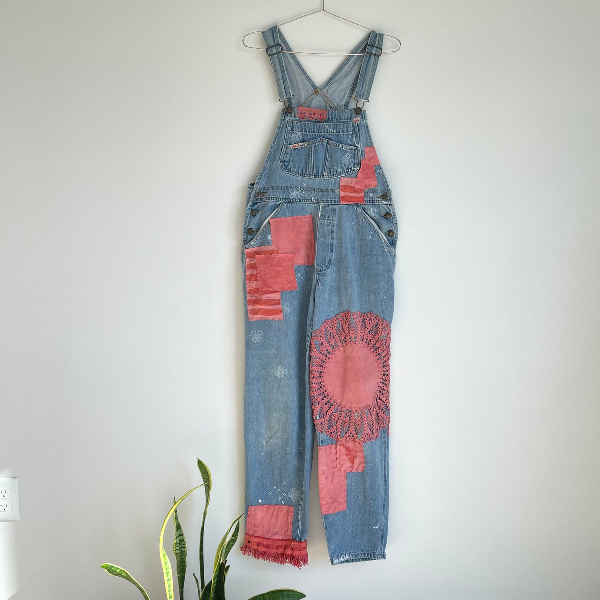 A pair of denim overalls hanging on a wall.