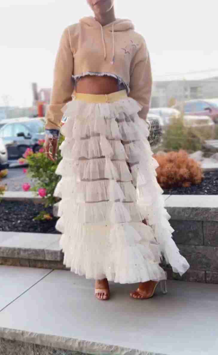 a woman standing on a sidewalk wearing a skirt.