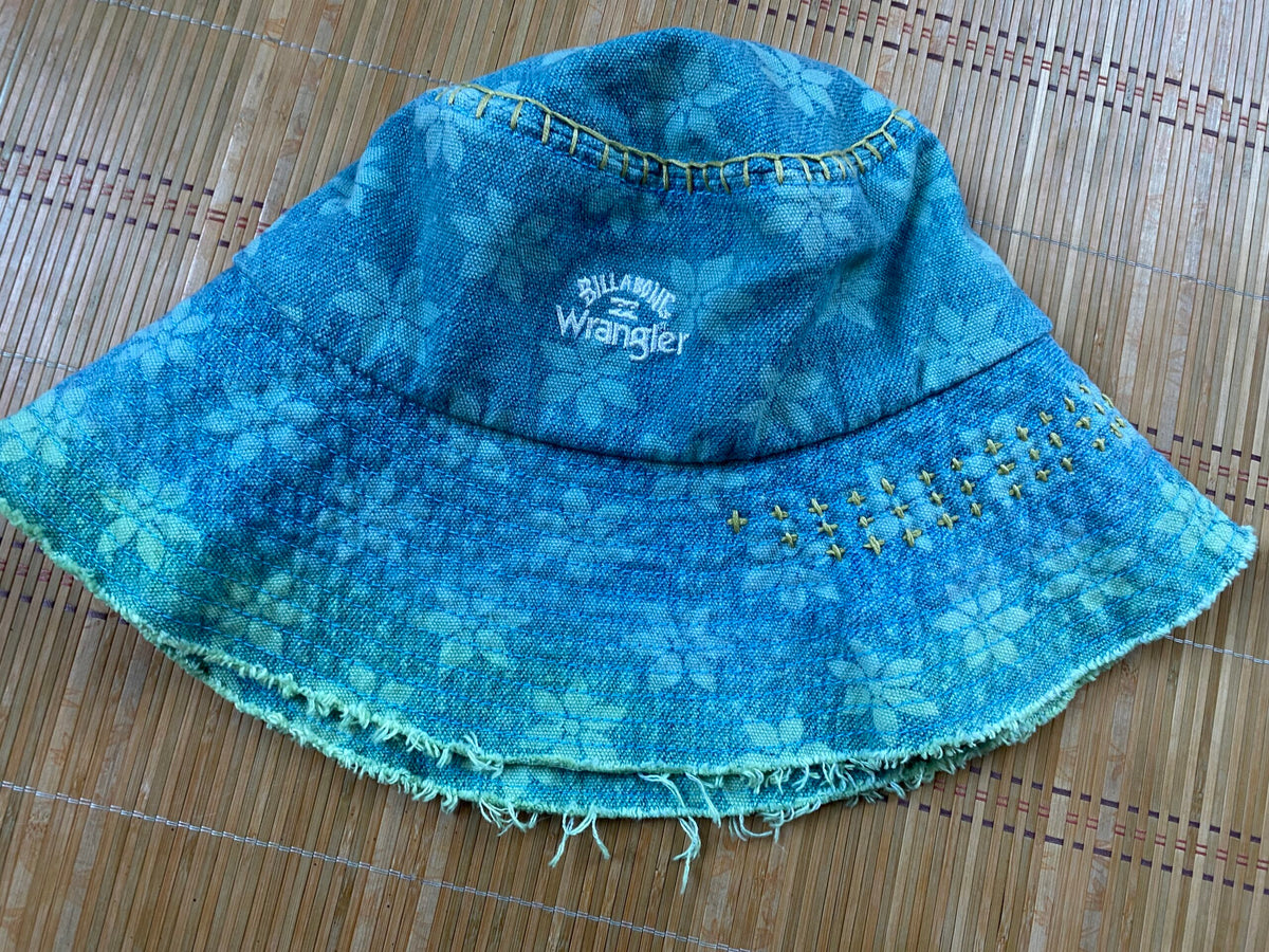 A blue denim bucket hat on a bamboo mat.