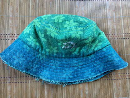A green and blue bucket hat on a bamboo mat.