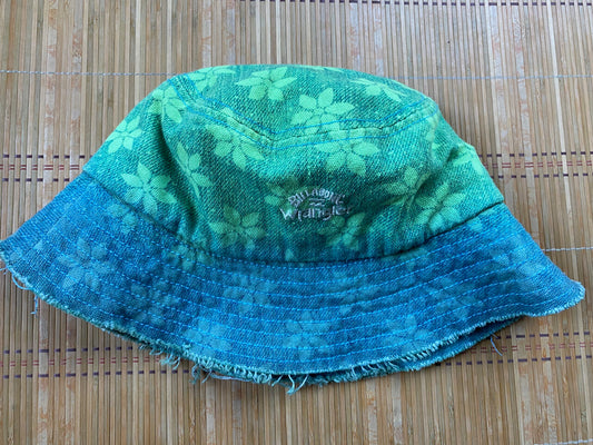 A green and blue bucket hat on a bamboo mat.
