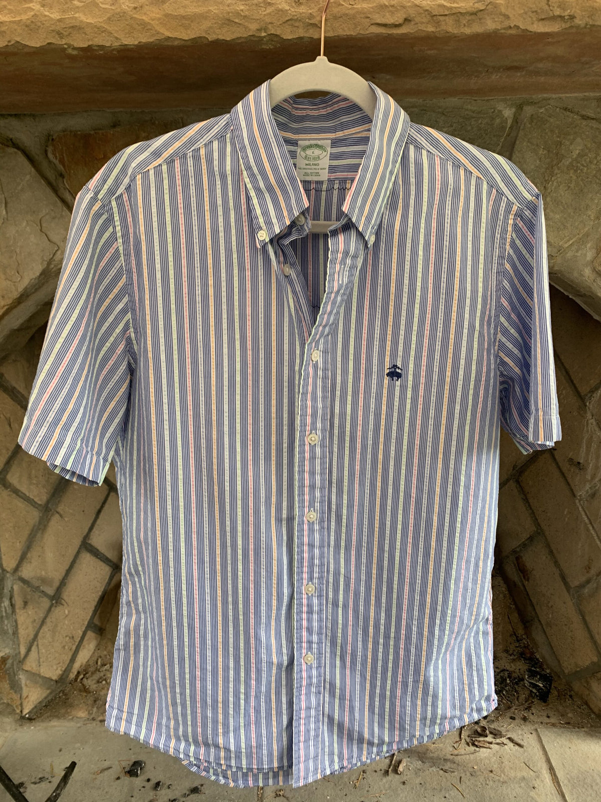 A Nirvana mens pinstriped button up shirt hanging on a wall.