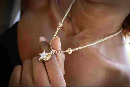 a woman holding a star necklace in her hand.