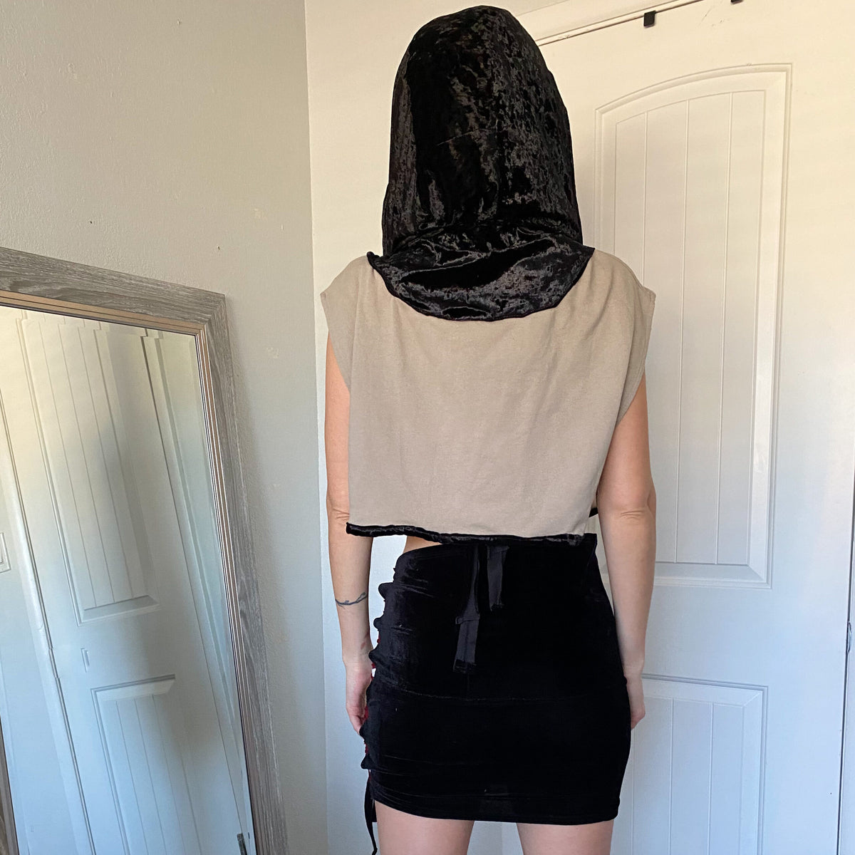 A woman wearing a black hoodie and black skirt.